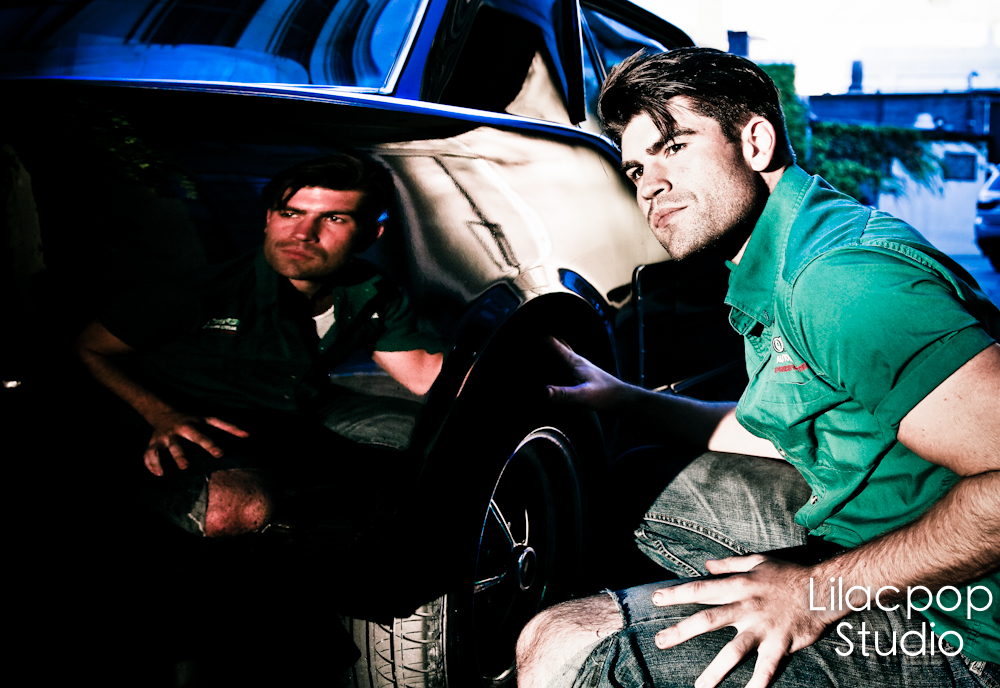 Michael Boryca Jr and a friend in work shirts beside a classic car at night
