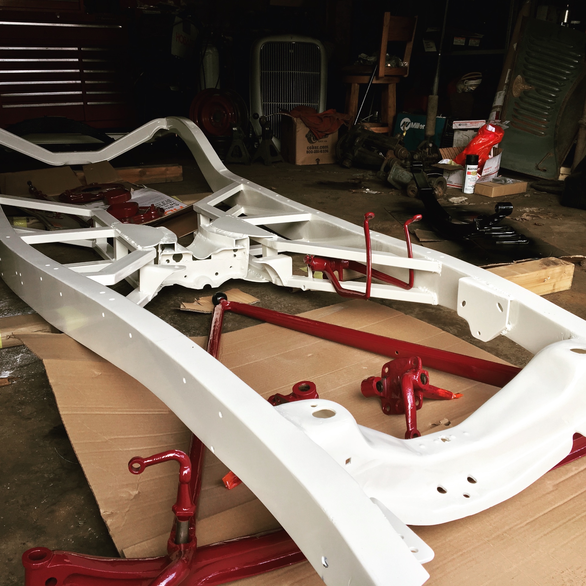 Freshly painted hot rod frame and red suspension components laid out on the shop floor